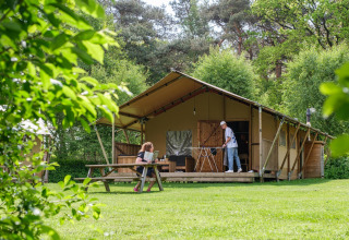 To personer nyder udendørs aktiviteter foran et safari-telt kaldet Vecht Glamping Lodge i Beerze Bulten.
