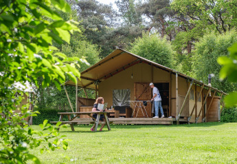 Dos personas disfrutan al aire libre frente a la tienda safari Vecht Glamping Lodge en Beerze Bulten, Países Bajos.