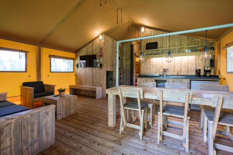 Vista interior de la Vecht Glamping Lodge en Beerze Bulten, Países Bajos, con muebles rústicos de madera.
