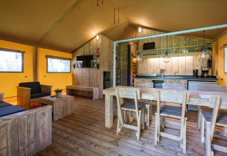 Vista interior de la Vecht Glamping Lodge en Beerze Bulten, Países Bajos, con muebles rústicos de madera.