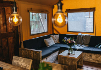 Area soggiorno accogliente presso Vecht Glamping Lodge, Beerze Bulten, con arredi rustici e luce calda.