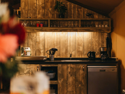 Acogedora cocina en Vecht Glamping Lodge, Beerze Bulten, Países Bajos, con paneles de madera y electrodomésticos.