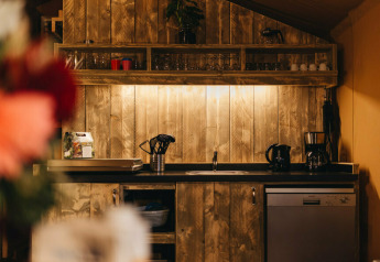 Acogedora cocina en Vecht Glamping Lodge, Beerze Bulten, Países Bajos, con paneles de madera y electrodomésticos.
