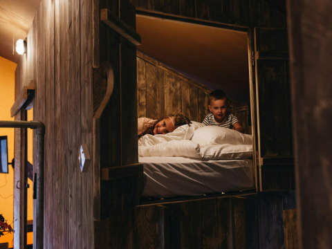 Dos niños se relajan en una cama elevada en Vecht Glamping Lodge, Beerze Bulten, Países Bajos.
