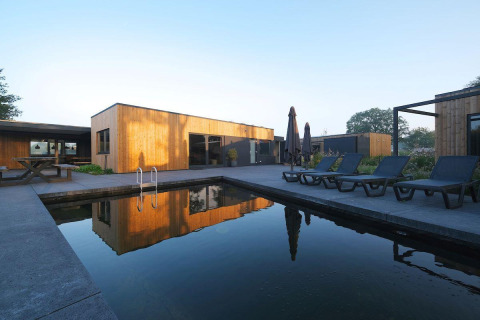 Moderne lodge Amalia Familia met houten gevel en privézwembad bij Hofparken Wiltershaar, Nederland.