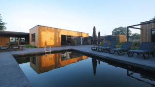 Modern Amalia Familia lodge with a wooden facade, sun loungers, and private pool at Hofparken Wiltershaar, Netherlands.