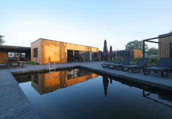 Modern Amalia Familia lodge with a wooden facade, sun loungers, and private pool at Hofparken Wiltershaar, Netherlands.