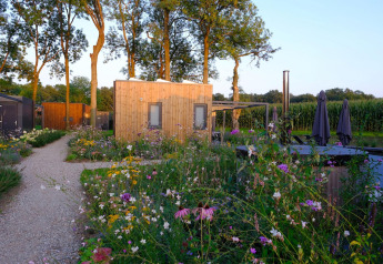 Knus houten huisje bij Amalia Familia in Hofparken Wiltershaar, Nederland, omringd door bloemen en bomen.