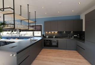 Cocina moderna en la cabaña Amalia Familia en Hofparken Wiltershaar, Países Bajos, con muebles oscuros.
