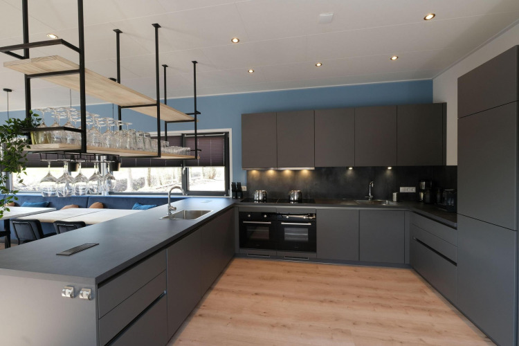 Cocina moderna en la cabaña Amalia Familia en Hofparken Wiltershaar, Países Bajos, con muebles oscuros.