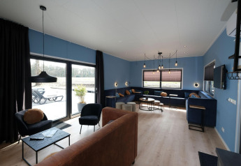 Gezellige woonkamer met blauwe muren en grote ramen bij Amalia Familia, Hofparken Wiltershaar, Nederland.
