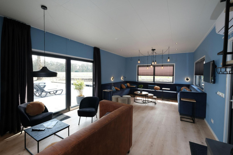 Modernes Wohnzimmer mit blauen Wänden und großen Fenstern im Amalia Familia, Hofparken Wiltershaar, Niederlande.