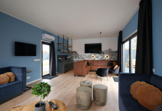 Sala moderna de la cabaña Amalia Familia en Hofparken Wiltershaar, Países Bajos, con paredes azules y mobiliario elegante.