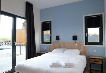 Moderne slaapkamer in de Amalia Familia lodge, Hofparken Wiltershaar, Nederland, met groot tweepersoonsbed.