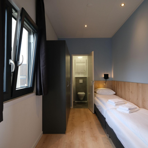 Modern lodge room at Amalia Familia, Hofparken Wiltershaar, Netherlands, with single bed and small bathroom.