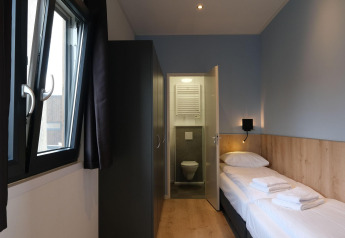 Modern lodge-kamertje in Amalia Familia, Hofparken Wiltershaar, Nederland, met eenpersoonsbed en badkamer.