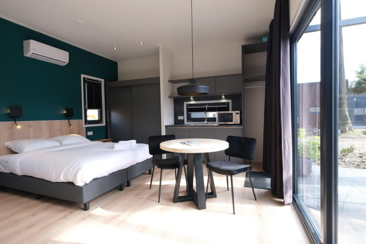 Interior moderno de lodge con cama, mesa y cocina en Hofparken Wiltershaar, Países Bajos.