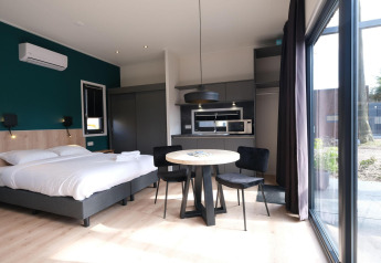 Modern lodge-interieur met bed, eettafel en kitchenette bij Hofparken Wiltershaar in Nederland.