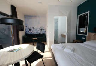 Habitación de lodge moderna en Amalia Familia, Hofparken Wiltershaar, con cama, sofá y baño privado.