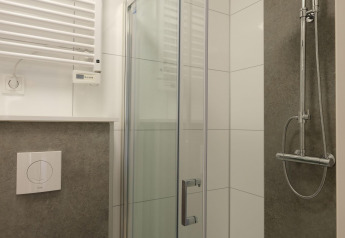 Moderne douchecabine met glazen deur en regendouche bij Amalia Familia, Hofparken Wiltershaar, Nederland.