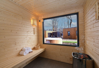 Interior de sauna de madera en Amalia Familia, Hofparken Wiltershaar, Países Bajos, con vista exterior.
