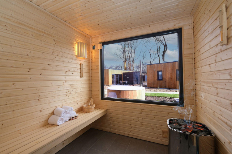 Interior de sauna de madera en Amalia Familia, Hofparken Wiltershaar, Países Bajos, con vista exterior.
