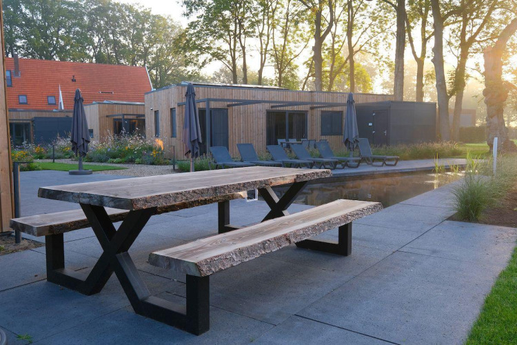 Holztisch mit Bänken draußen bei der Amalia Familia-Lodge im Hofparken Wiltershaar, Niederlande, Sonnenaufgang.