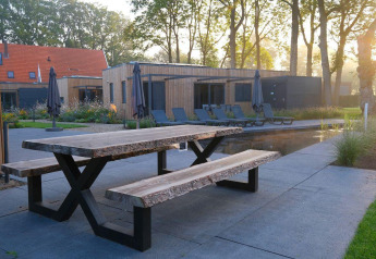 Picknicktafel in hout bij Amalia Familia, Hofparken Wiltershaar, Nederland, in het ochtendlicht.