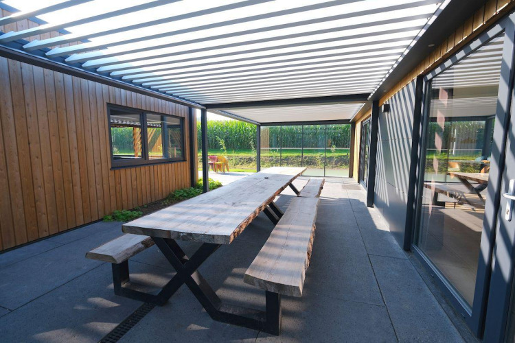 Área de comedor exterior con banco y mesa de madera en Amalia Familia, Hofparken Wiltershaar, Países Bajos.