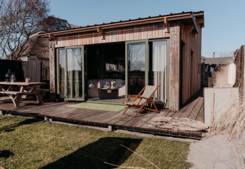 Foto de la cabaña Juttershut en Duynpark Het Zwanenwater, Países Bajos, con terraza y muebles al aire libre.