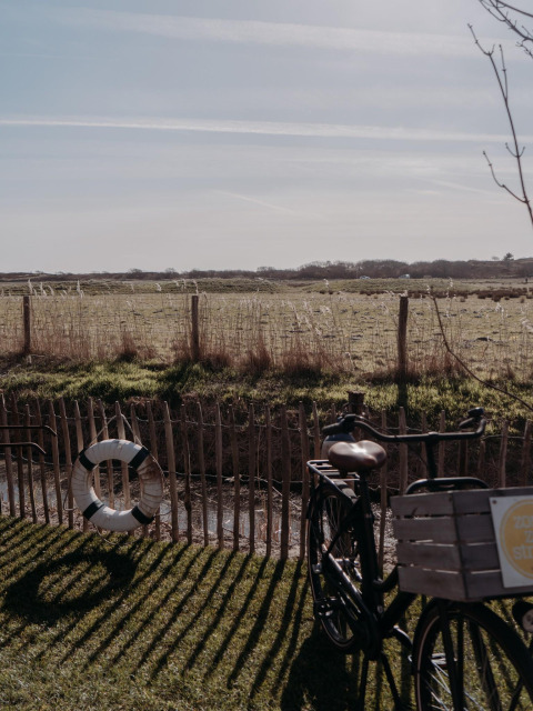 Een fiets staat bij een hek aan een veld bij Juttershut Lodge, Duynpark Het Zwanenwater, Nederland.