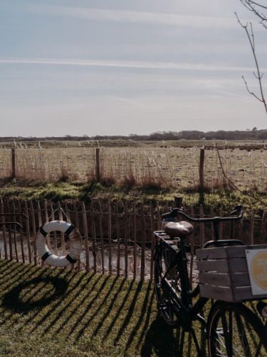 Ein Fahrrad steht am Zaun eines Feldes bei der Juttershut Lodge, Duynpark Het Zwanenwater, Niederlande.