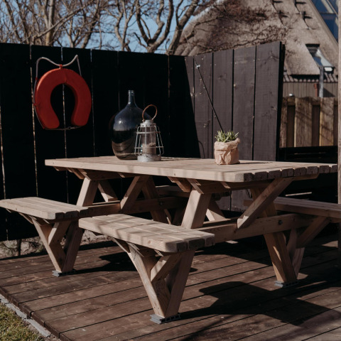 Picknicktafel met banken op een houten terras bij Juttershut, Duynpark Het Zwanenwater, Nederland.