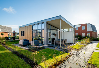 Moderne tiny house Knilles Luxe ved Tusken de Marren, Holland, med terrasse og have i solskin.