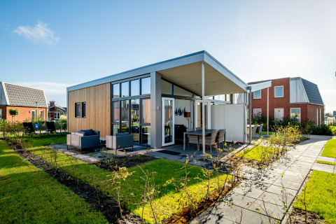 Moderne tiny house Knilles Luxe bij Tusken de Marren in Nederland met een terras en zonnige tuin.