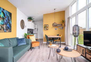 Bright, modern tiny house Knilles Luxe at Tusken de Marren with bold yellow accents and large windows.