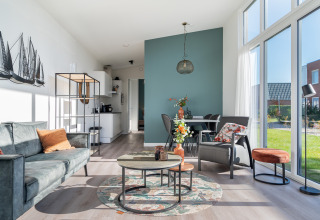 Sala luminosa de la tiny house Knilles Luxe en Tusken de Marren, con muebles modernos y grandes ventanales.