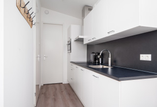 Modern narrow white kitchen with black countertop in Knilles Luxe tiny house at Tusken de Marren, Netherlands.