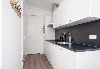 Modernes, kleines weißes Kücheninterieur mit schwarzen Arbeitsplatten in einem Tiny House in den Niederlanden.