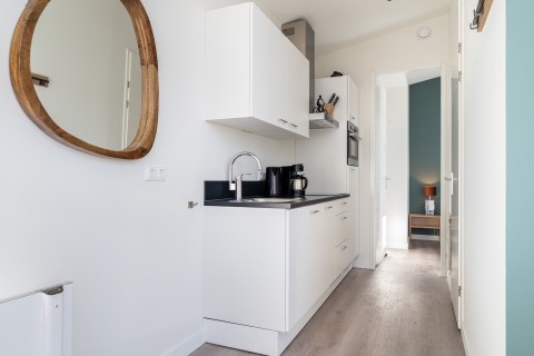Cocina moderna y estrecha con gabinetes blancos en la tiny house Knilles Luxe en Tusken de Marren, Países Bajos.