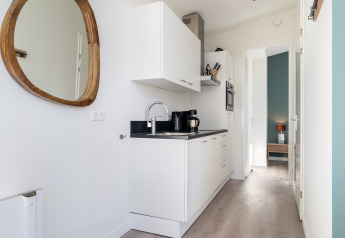 Modern, narrow kitchen with white cabinets inside Knilles Luxe tiny house at Tusken de Marren, Netherlands.
