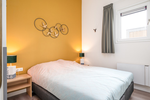 Dormitorio moderno y luminoso en Knilles Luxe tiny house, Tusken de Marren, Países Bajos, con pared amarilla.