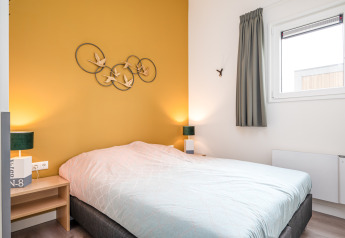 Camera da letto moderna e luminosa in Knilles Luxe tiny house a Tusken de Marren, Paesi Bassi, parete gialla.