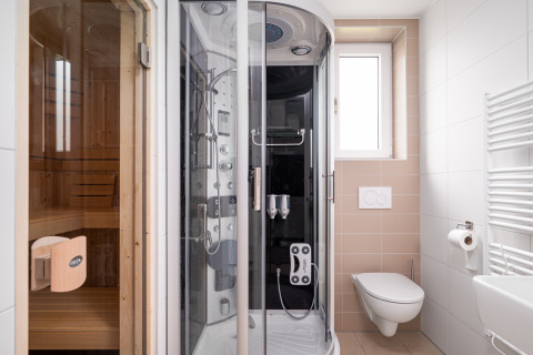 Baño moderno en la tiny house Knilles Luxe con sauna, ducha multifunción y váter suspendido en la pared.