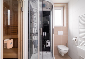 Bagno moderno nella tiny house Knilles Luxe con sauna, doccia multifunzione e WC sospeso alla parete.