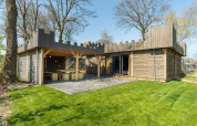Cabaña moderna de madera con diseño de castillo y patio, ubicada en Kampeerdorp de Zandstuve, Países Bajos.
