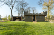 A wooden lodge designed like a castle with battlements at Kampeerdorp de Zandstuve in the Netherlands.