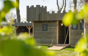Holzlodge im Burgenstil bei Castle Uylenburght, Kampeerdorp de Zandstuve, Niederlande, durch Blätter gesehen.