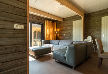 Modern lodge living room with grey sectional sofa and wood walls at Castle Uylenburght, Kampeerdorp de Zandstuve.