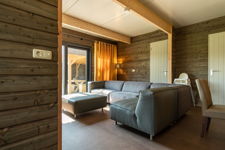 Modernes Wohnzimmer mit Ecksofa und Holzwänden in der Castle Uylenburght Lodge, Kampeerdorp de Zandstuve.